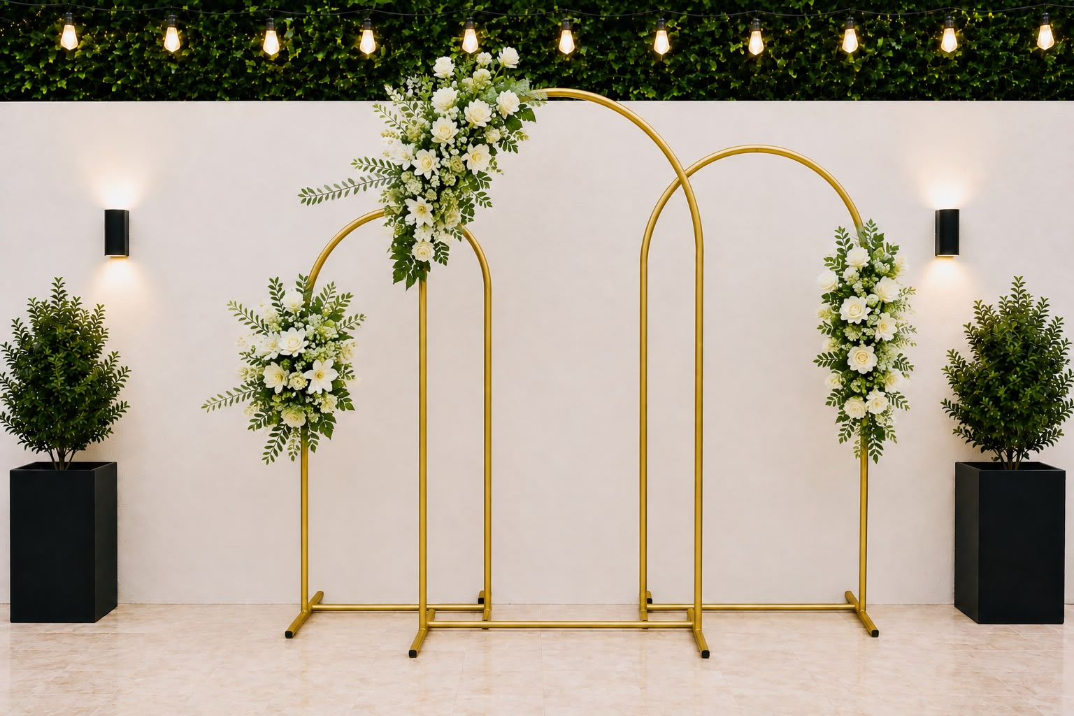 Arcos dorados con arreglos florales blancos y verdes montados frente a pared clara
