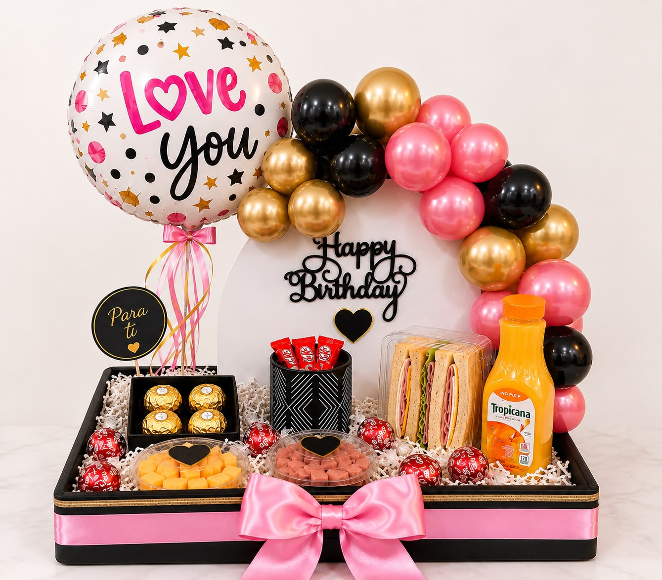 Bandeja de desayuno sorpresa con globo Love You, arco de globos rosados, dorados y negros, chocolates y sándwiches
