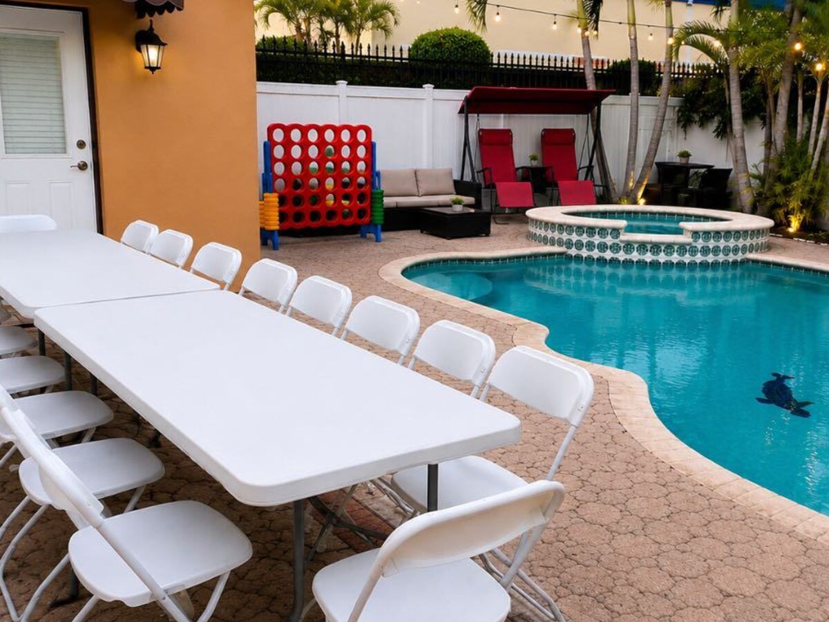 Mesas rectangulares de 6 ft con sillas blancas junto a la piscina